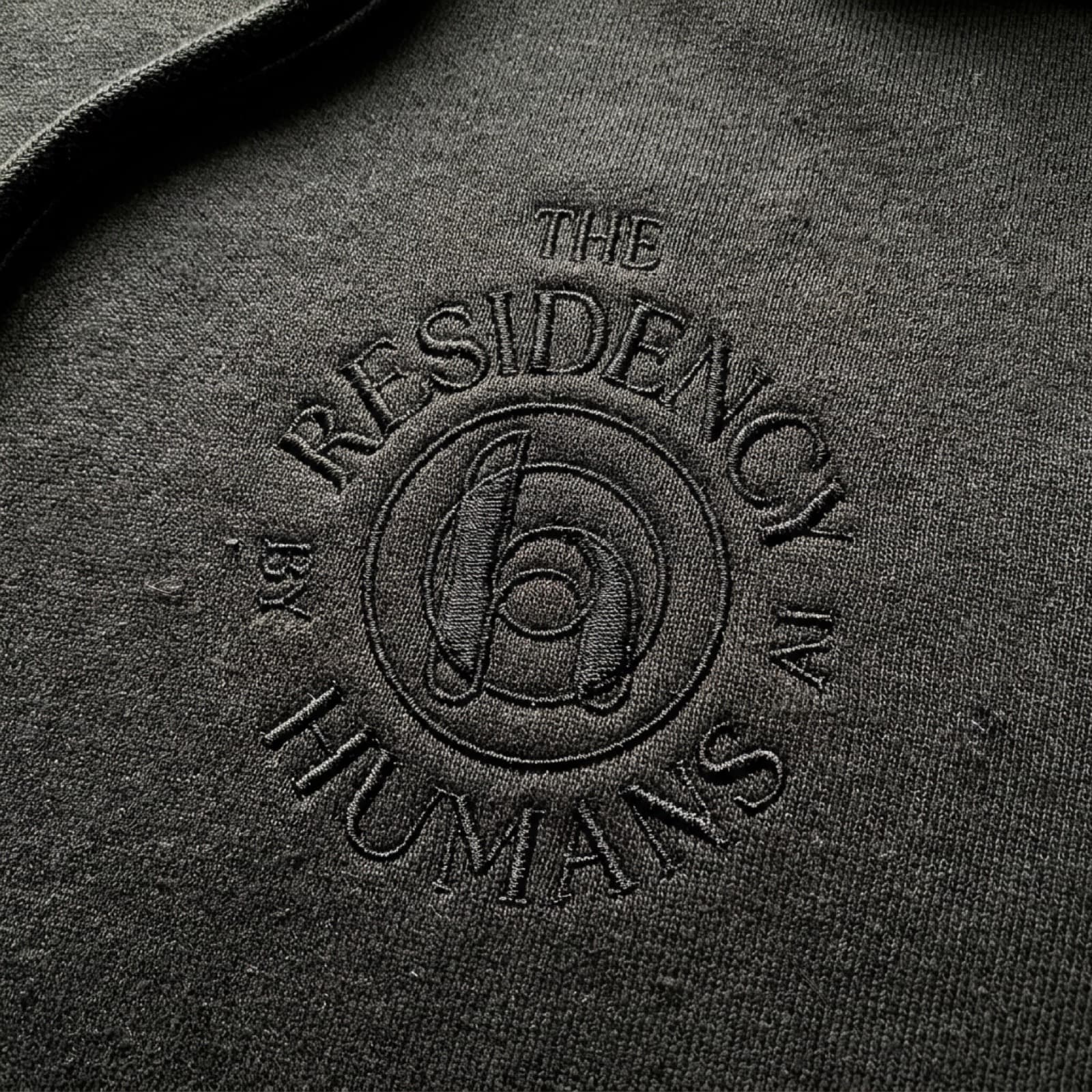 The Residency seal embroidered on a black hoodie